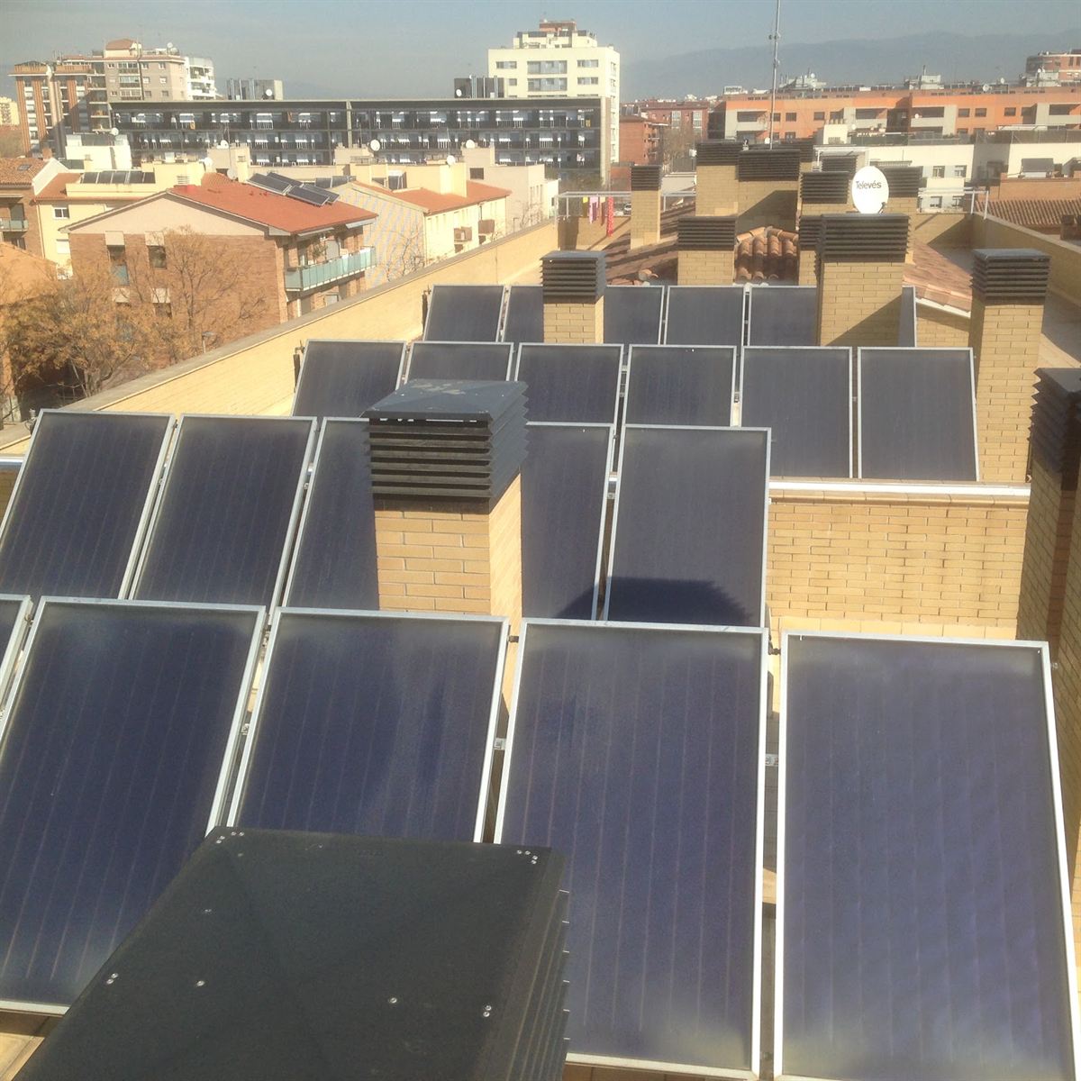 Batería de captadores solares planos en la cubierta de un edificio de viviendas